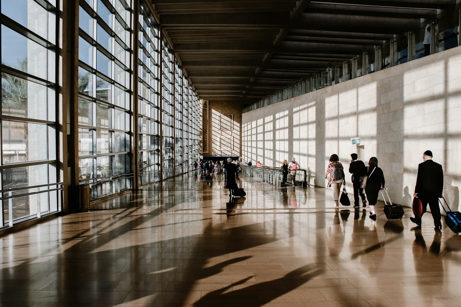 Voyageurs dans un terminal d'aéroport baigné de lumière.
